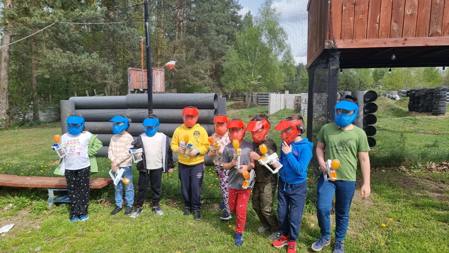 Dzieci w maskach ochronnych z markerami Gel Blaster na polu Paintball Sierpc
